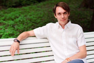 genç adam bir bankta oturur.