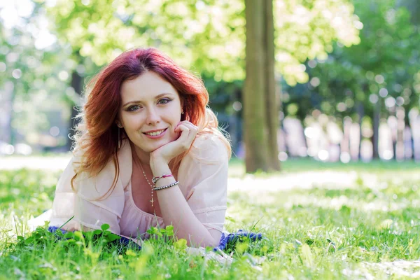 Jonge vrouw liggend op het gras — Stockfoto