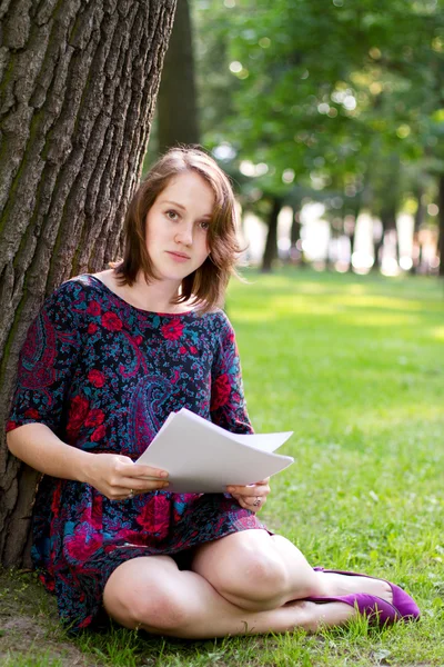 Młoda kobieta siedząca pod drzewem — Zdjęcie stockowe