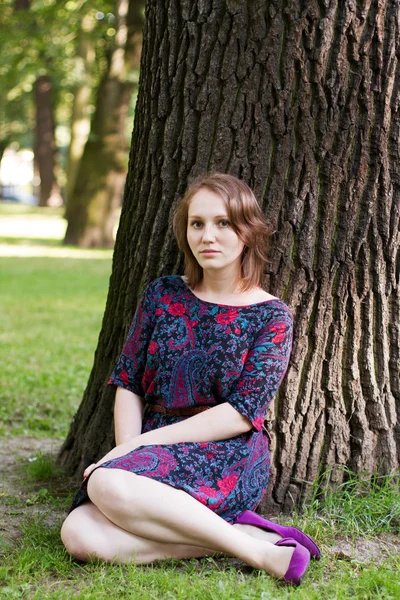 Jonge vrouw zitten onder een boom — Stockfoto