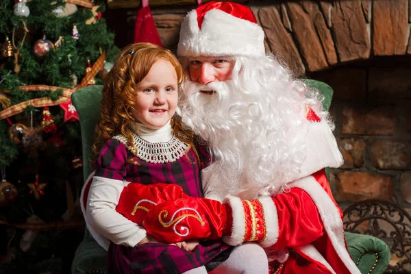 Санта-Клауса, сидячи на стільці з маленькою дівчинкою. — стокове фото