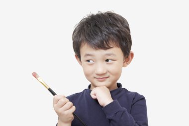 Asyalı çocuk çocuk boyama fırça beyaz arka plan ile tutar
