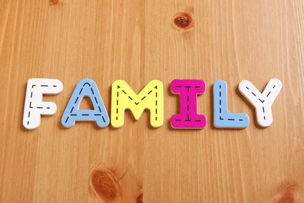 Familie, Zauber durch holzige Puzzlebuchstaben mit holzigem Hintergrund — Stockfoto