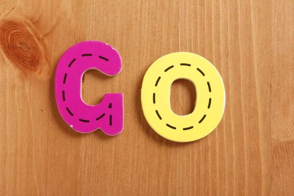 GO, spell by woody puzzle letters with woody background — Stock Photo, Image