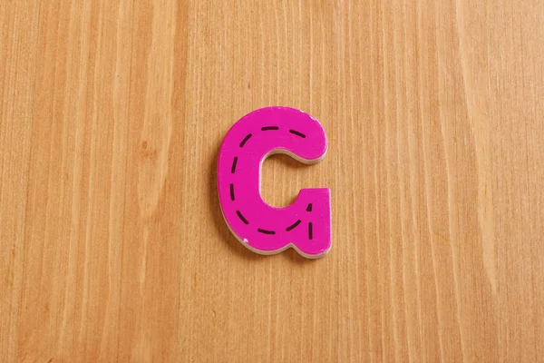 G, spell by woody puzzle letters with woody background — Stok Foto