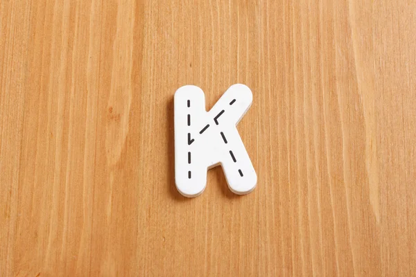 K, zaklęcie pismami zdrewniałe puzzle z Woodiego tło — Zdjęcie stockowe