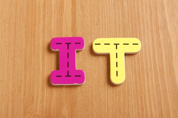 IT, incantesimo da lettere di puzzle legnose con sfondo legnoso — Foto Stock