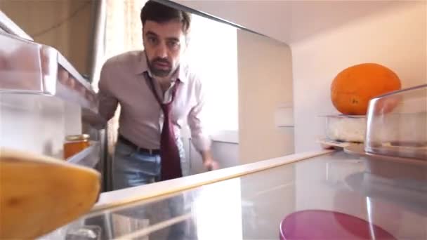 Hombre barbudo hambriento buscando comida en el refrigerador — Vídeos de Stock