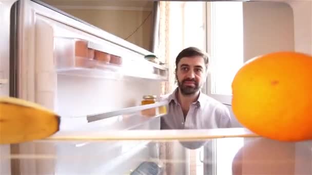 Uomo barbuto affamato in cerca di cibo in frigorifero — Video Stock