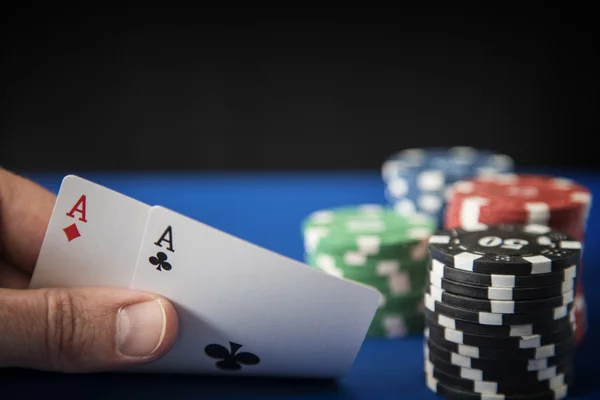 Dois ases na mão e fichas de jogo no casino feltro azul — Fotografia de Stock