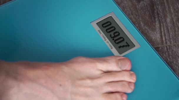 Manliga ben stående på en hem golv vikt skalor och på displayen Go Run — Stockvideo