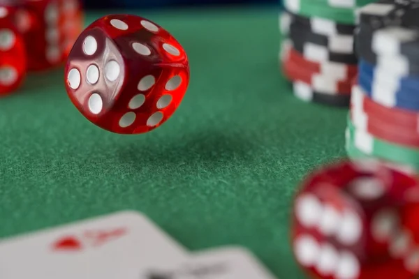 Dados vermelhos gira no ar, fichas de casino, cartões em feltro verde — Fotografia de Stock