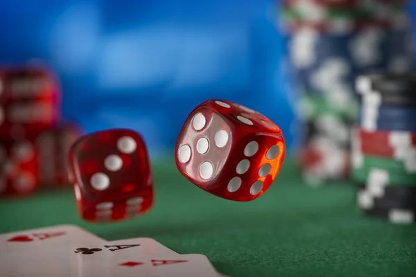 Два червоних кості обертаються в повітрі, фішки казино, карти на зеленому фетрі — стокове фото