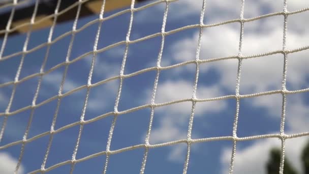 Мяч пляжного волейбола летит в сети на облачном фоне неба — стоковое видео