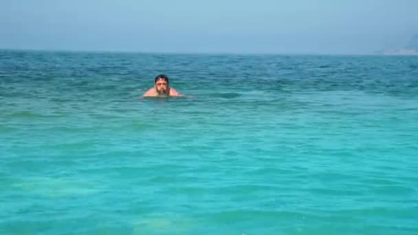 Young man comes out of the sea after swimming. — Stock Video