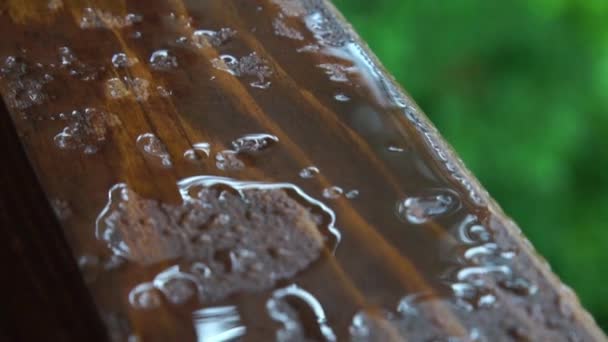 Rain drops on a wooden window sill like liquid metal or mercury — Stock Video