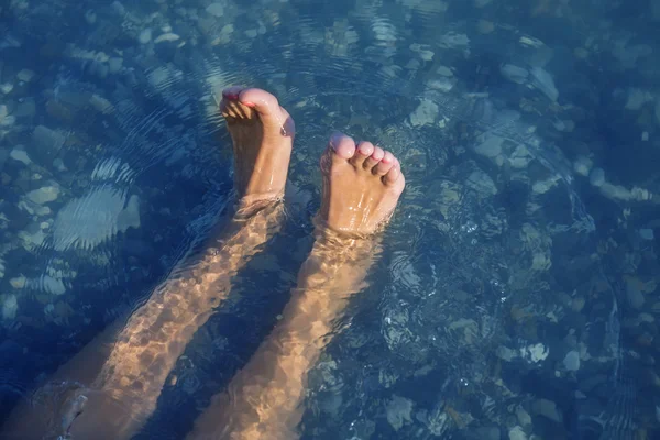 Молодые и красивые женские ноги с красными ногтями на пляже под волнами . — стоковое фото