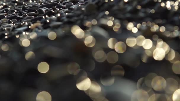 Close-up film kiezelstrand met golven en druppels. — Stockvideo
