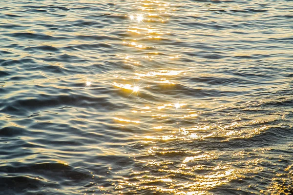Blue sea water surface at sunset with sparks