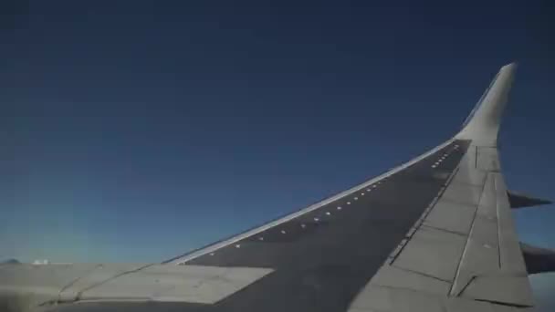 Flugzeug fliegt am blauen Himmel durch die weißen Wolken. Blick auf den Flugzeugflügel aus dem Fenster. — Stockvideo