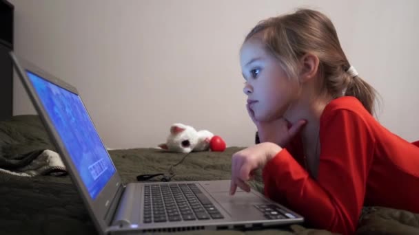 Little girl at night watching cartoons at computer. — Stock Video