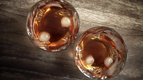 Lunettes de whisky avec glace sur table en bois. Vue supérieure avec espace de copie — Video