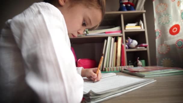 Маленька дівчинка пише і робить домашні завдання . — стокове відео