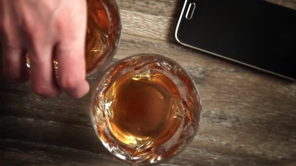 Gläser Whisky mit Eis auf Holztisch. — Stockvideo