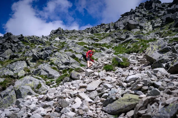 Mujer joven descendiendo en un terreno montañoso difícil . — Foto de Stock