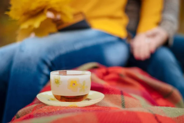 A cup of hot tea, a drink in the forest in the fall on vacation. Aged married couple. Hands close-up. Together