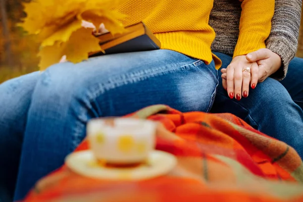 Bir fincan sıcak çay, tatilde sonbaharda ormanda bir içki. Yaşlı evli bir çift. Eller yakın çekim. Birlikte