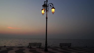 Retro sokak lambası ve Lazise 'de Garda Gölü gezinti güvertesinde iki bank, Kasım 2020' de öğleden sonra.