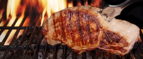 Filete de lomo de cerdo en parrilla de barbacoa de llama caliente con tenedor —  Fotos de Stock