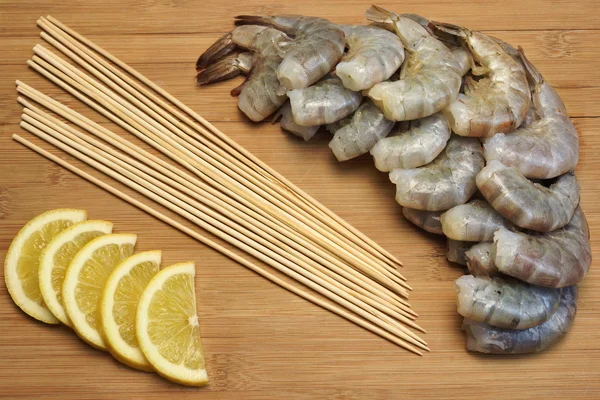 Many Raw  Shrimps On Skewer With Lemon On Wooden Background — Stock Photo, Image