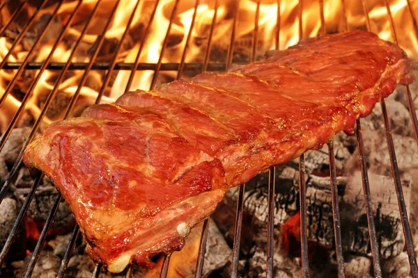 Svinekjøtt tilbake eller spareribs på BBQ-grill med flammer – stockfoto