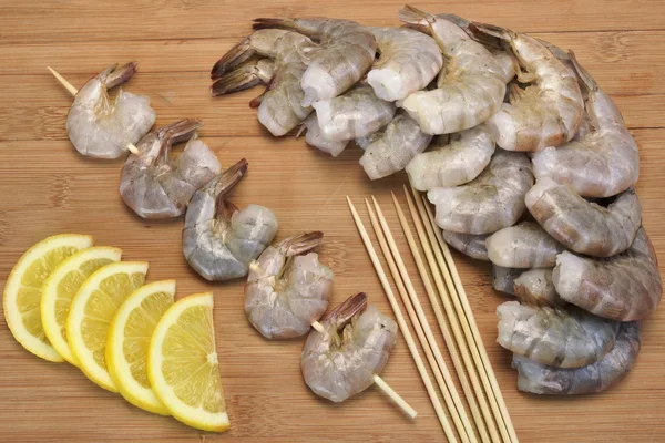 Many Raw  Shrimps On Skewer With Lemon On Wooden Background — Stock Photo, Image