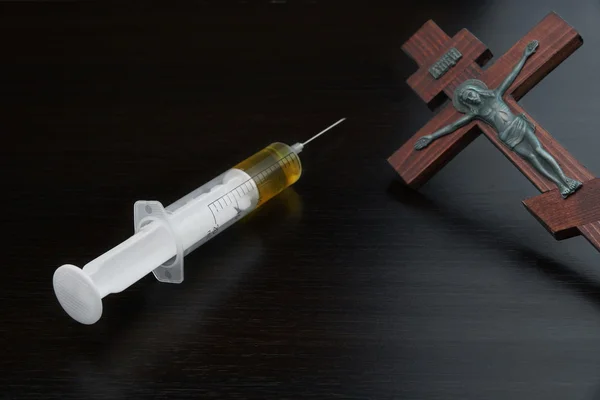 Syringe with Yellow Liquid And Crucified Jesus on Wooden Cross — Zdjęcie stockowe