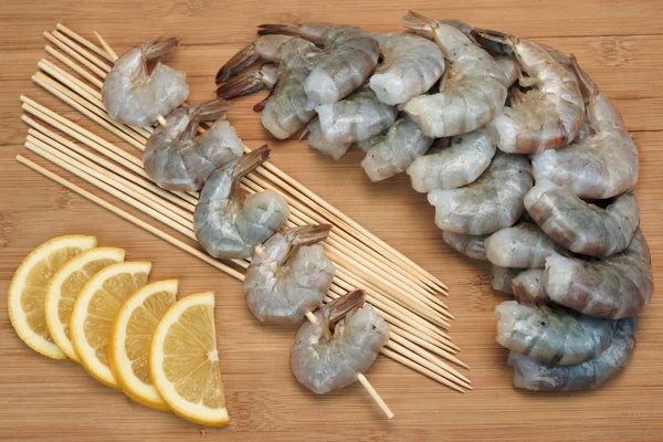 Many Raw  Shrimps On Skewer With Lemon On Wooden Background — Stock Photo, Image