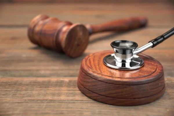 Stetoscope and Real Judges Gavel On Brown Wooden Background — Stock Photo, Image