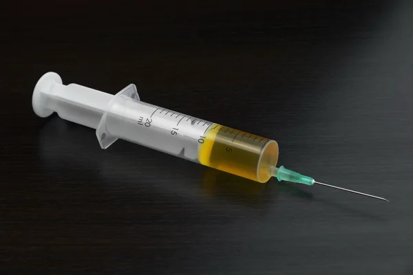 Single Syringe With Yellow Liquid On The Black Wood  Background — Stock Photo, Image