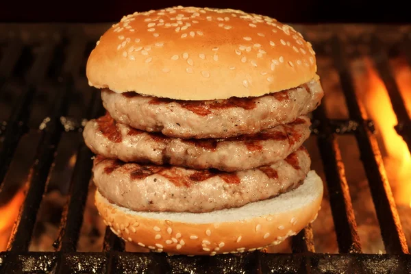 Hambúrguer grande caseiro na churrasqueira em chamas quente — Fotografia de Stock