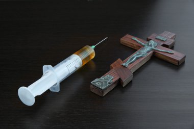 Jesus Crusified Figurine and Syringe With Liquid on Black Backgr clipart