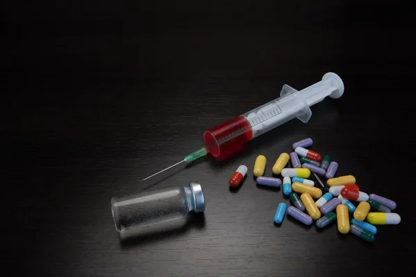 カラフルな錠剤、シリンジ、アンプルとブラックバックグルーの液体 — ストック写真