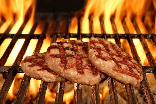 Trois hamburgers dorés faits maison sur le barbecue chaud flamboyant — Photo