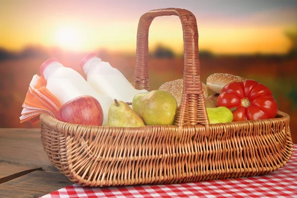 Cesta de piquenique com comida e bebida na mesa — Fotografia de Stock