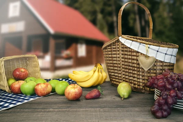 Piknik masa iki sepet ve meyve yakınındaki kır evi — Stok fotoğraf