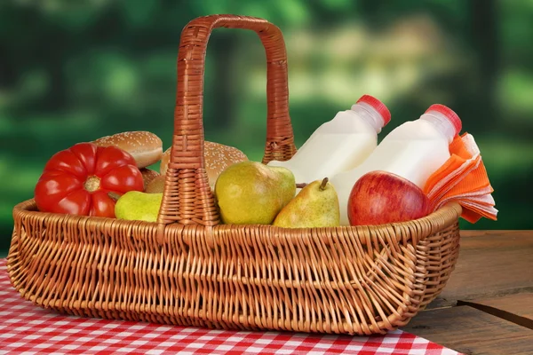 Cesta de picnic con comida y bebida en la mesa — Foto de Stock