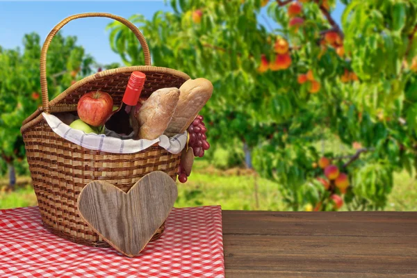 Picknickmand met eten en drinken op de houten tafel — Stockfoto