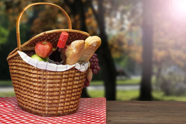 Cesta de picnic con comida y bebida en la mesa de madera —  Fotos de Stock