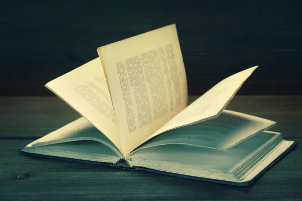 Livro Shabby velho aberto com texto desfocado em fundo de madeira — Fotografia de Stock